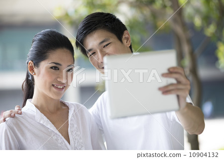 Asian couple using tablet to take a selfie. Asian couple using tablet to take a selfie. 10904132