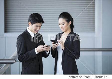 Two Asian business colleagues using smartphone's. Two Asian business colleagues using smartphone's. 10904139