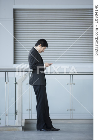 Asian Businessman using a Cell Phone to send a text. Asian Businessman using a Cell Phone to send a text. 10904140