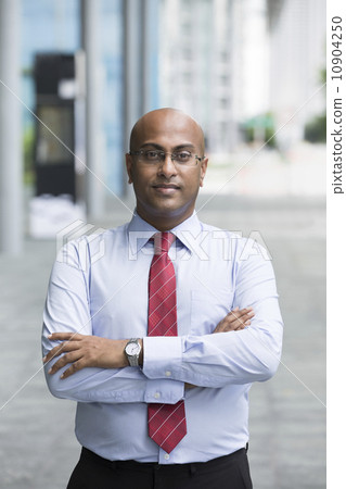 Confident Indian Business man standing in modern city 10904250