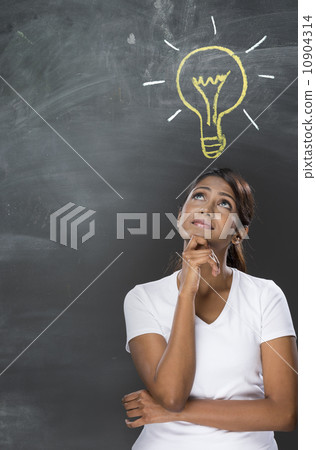 Indian woman standing in front of chalkboard with light bulb dra 10904314