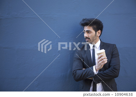 Indian businessman leaning against a stone wall. 10904638