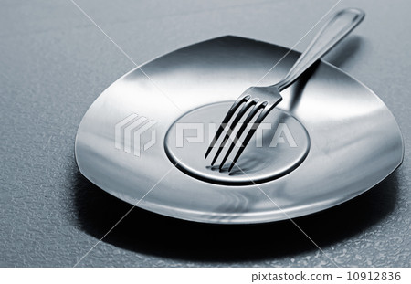 Empty steel plate with fork on the table. Monochrome photo with shallow depth of field 10912836