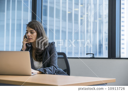 Asian executive in a jacket making a call in the office.  10913726