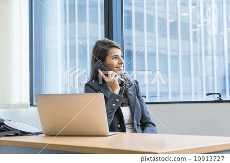 Asian executive in a jacket making a call in the office. Asian executive in a jacket making a call in the office. 10913727