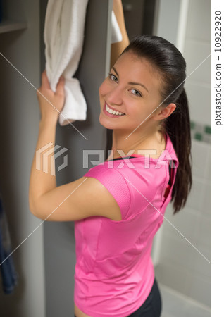Woman placing towel on open locker door Woman placing towel on open locker door 10922920