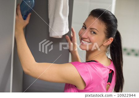 Woman putting water bottle in locker 10922944