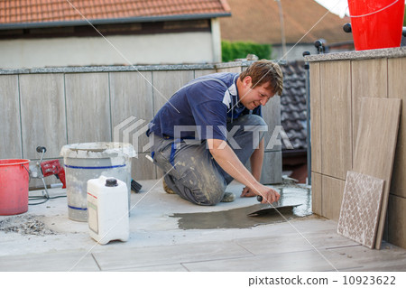 Young man tiling on balkony ceramic tiles 10923622