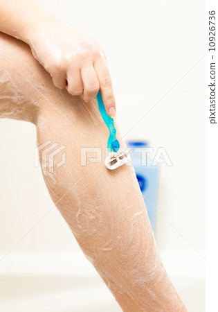 woman shaving leg with blue razor woman shaving leg with blue razor 10926736