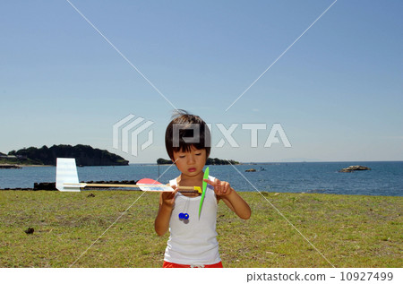 Children flying a model plane on the coast 10927499