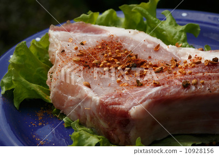 Raw pork steak sprinkled with pepper on blue plate with salad 10928156