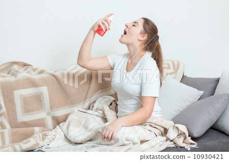 Sick woman lying in bed and using throat spray Sick woman lying in bed and using throat spray 10930421