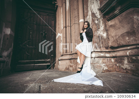 Woman in long white dress leaning against ancient wall of abbey Woman in long white dress leaning against ancient wall of abbey 10930634