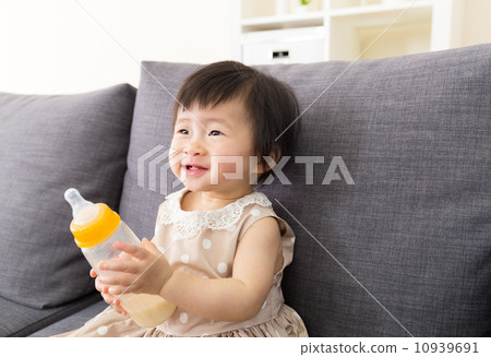 Asia baby holding milk bottle at home 10939691