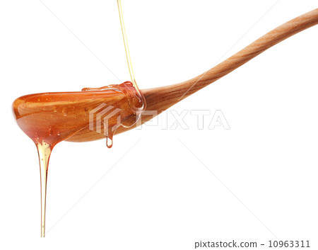 Honey dripping from a wooden honey dipper isolated on white back 10963311