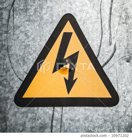 High voltage triangle sign mounted on gray metal wall 10971202