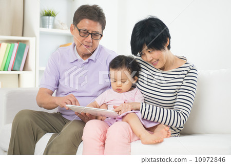 asian grand parents teaching grand son with tablet 10972846