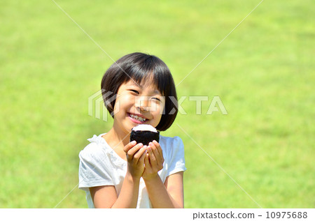 A girl who eats onigiri at the lawn plaza 10975688