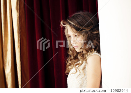Charming girl shyly posing on curtain background Charming girl shyly posing on curtain background 10982944
