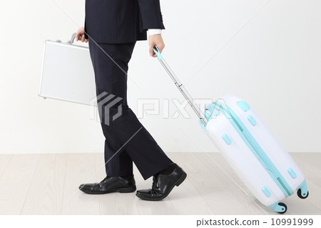 The feet of a businessman drawing a suitcase 10991999