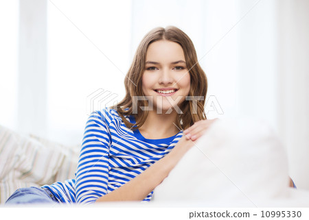 smiling teenage girl sitting on sofa at home smiling teenage girl sitting on sofa at home 10995330