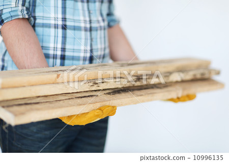 close up of male in gloves carrying wooden boards close up of male in gloves carrying wooden boards 10996135