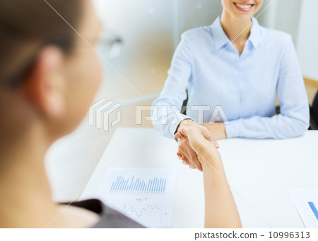 two smiling businesswoman shaking hands in office two smiling businesswoman shaking hands in office 10996313