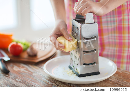 close up of female hands grating cheese 10996935