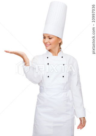 smiling female chef holding something on hand smiling female chef holding something on hand 10997036