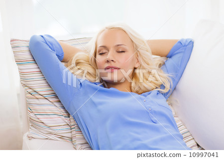 smiling young woman lying on sofa at home 10997041