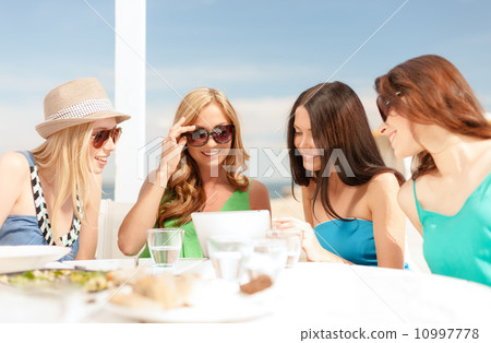 smiling girls looking at tablet pc in cafe 10997778