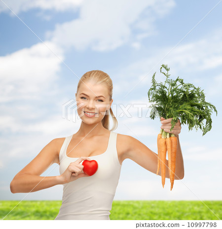 smiling woman holding heart symbol and carrots smiling woman holding heart symbol and carrots 10997798