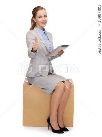 woman sitting on cardboard box with tablet pc 10997803