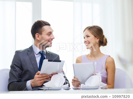 couple with menus on tablet pc at restaurant couple with menus on tablet pc at restaurant 10997820