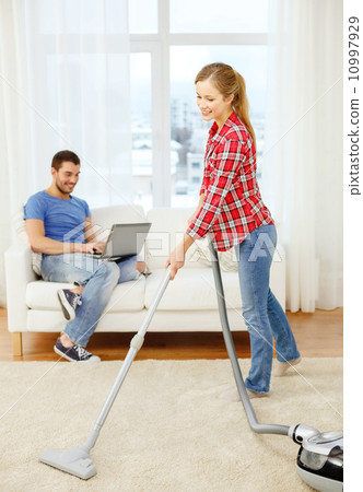 smiling woman with hoover and man with laptop 10997929