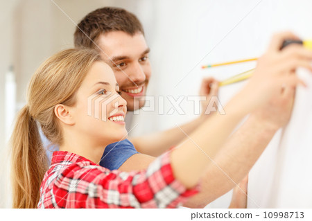 smiling couple measuring wall 10998713