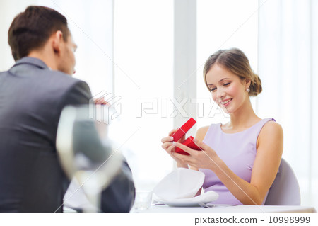 excited young woman looking at boyfriend with box 10998999