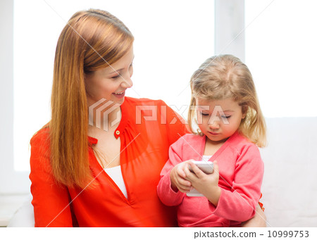happy mother and daughter with smartphone at home happy mother and daughter with smartphone at home 10999753