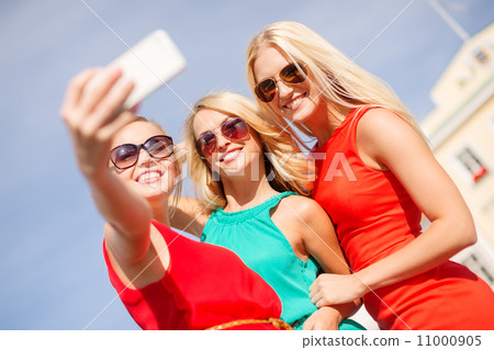 smiling girls taking photo with smartphone camera 11000905