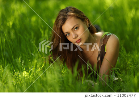 brunette lying on green grass brunette lying on green grass 11002477