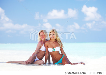 girls sitting on ocean coast 11003989