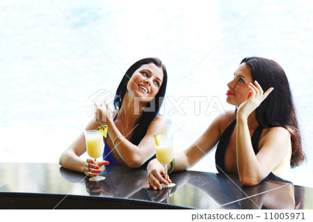 Two women with cocktails in swimming pool 11005971