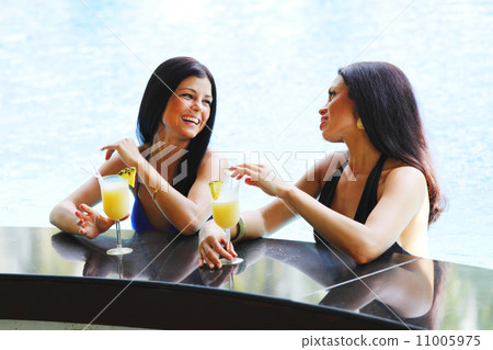 Two women with cocktails in swimming pool 11005975