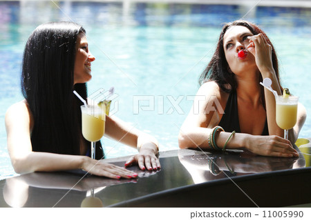 Two women with cocktails in swimming pool 11005990