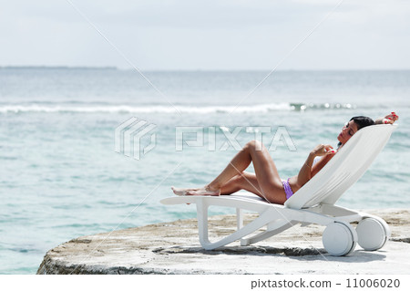 Woman in chaise-lounge near sea 11006020