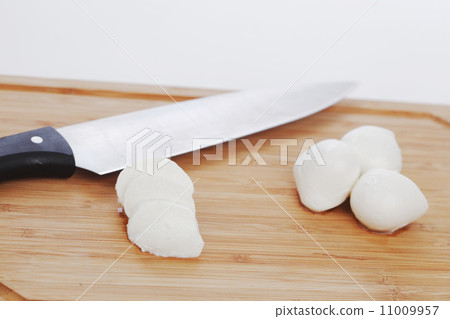 Sliced mozzarella with knife on wooden board Sliced mozzarella with knife on wooden board 11009957