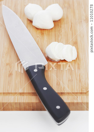 Sliced mozzarella with knife on wooden board Sliced mozzarella with knife on wooden board 11010278