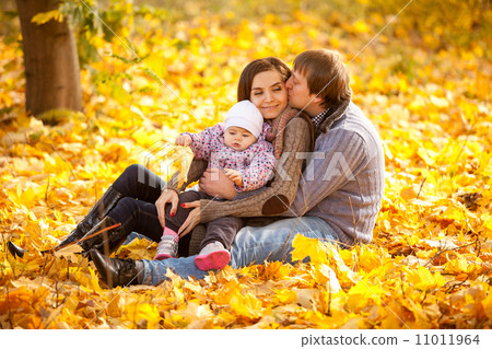 Young man hugging daughter and wife on leaves Young man hugging daughter and wife on leaves 11011964