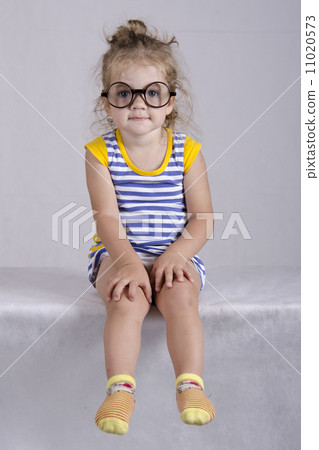 Two-year-old girl funny glasses sitting looking in frame 11020573