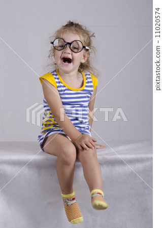Two-year-old girl in funny glasses sits and laughs cheerfully 11020574